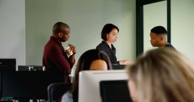 Ofiste bilgisayar üzerinde tartışırken iş arkadaşları bir çok etnik grup uzak manzara. Ortak çalışanlar konuşurken ve birlikte çalışma.