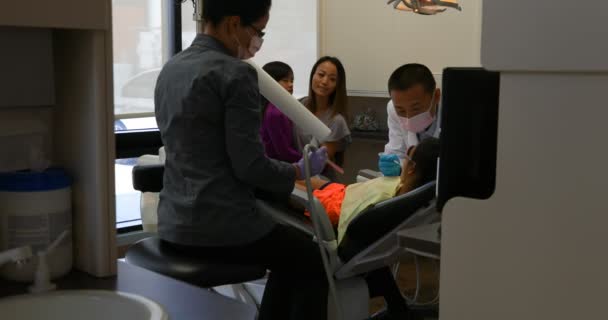 男性牙医在临床上用工具检查病人的前面视图 当牙医检查她的时候女孩很紧张 — 图库视频影像