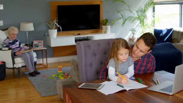 自宅のリビング ルームで彼女の研究で父を助ける少女 父と娘の宿題を一緒にやって — ストック動画