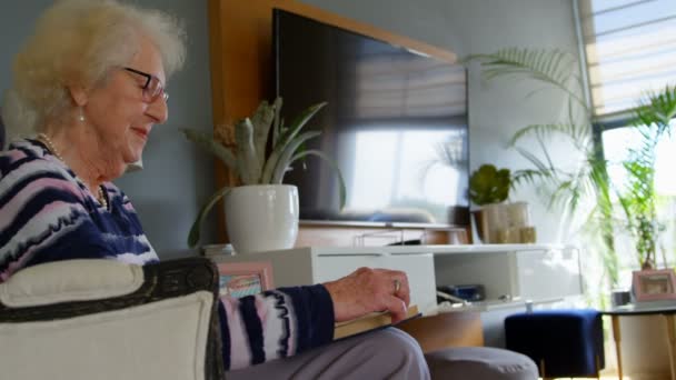 Närbild Senior Pensionerad Kvinna Som Bär Glasögon Bok Vardagsrummet Hemma — Stockvideo