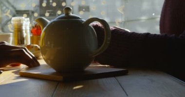 Bir kafede çay yudumlarken elele sevimli çok etnik gruptan oluşan çiftin yakın çekim. Güneşli bir brunch sahip. Yavaş çekimde