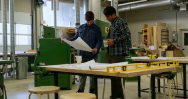 Düşük açılı görünüş erkek kahve yaparken atölye, planı üzerinde tartışırken marangoz