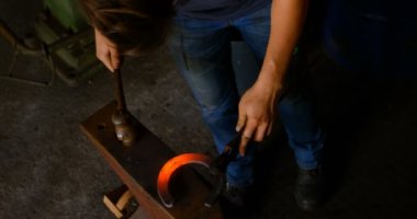 Havai nal fabrikasında kalıplama kısa saçlı Genç kadın metal. O parlayan sıcak nal çekiçle vurdu.