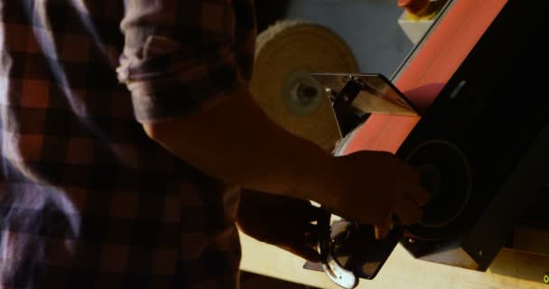 工厂里一名年轻的女金属匠在马蹄铁上使用磨刀机的后视 — 图库视频影像
