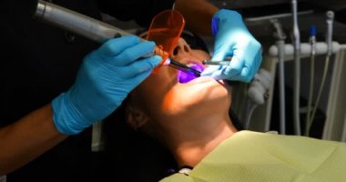 Yüksek açı close-up diş kliniği araçlarında bir hastayla inceleyerek Asya diş hekimi. Mavi Cerrahi eldivenler ve çok dikkatli bir şekilde çalışan diş hekimi.