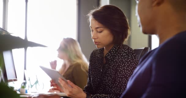 Vue latérale de jeunes collègues d'affaires multiethniques utilisant une tablette numérique au bureau. Joyeux collègue qui travaille ensemble .