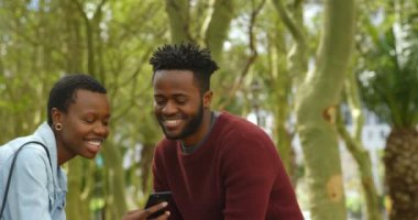 Cep telefonuyla şehirde neşeli çift yan görünüm. Bir kaç telefon bir şey hakkında gülüyor. Yavaş çekimde