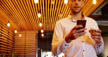 Genç bir çekici erkek yönetici kafeteryada kahve yaparken cep telefonunuzun görünümünü düşük açılı.
