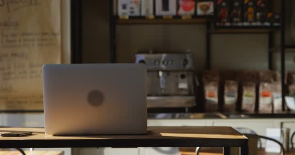 在现代咖啡馆里 笔记本电脑和手机躺在一张桌子上 背景是咖啡机 周围环绕着各种美味的未开封咖啡 慢动作 — 图库视频影像
