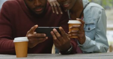 Genç çift sahip götürün kahve açık kafede iken cep telefonunuzu kullanarak Close-up. Yavaş çekimde
