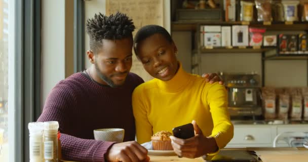 カフェで幸せなカップルの撮影 Selfie のフロント ビュー カフェテリアでコーヒーを飲んでカジュアルな服を着てかわいいカップル — ストック動画