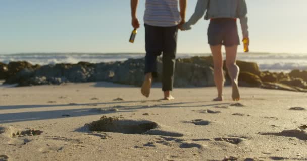 Пара Держащихся Руки Бутылкой Пива Идущей Пляжу Следы Песке — стоковое видео