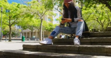 Cep telefonuyla şehirde kadın genç dansçı. Ağaçlar ve şehir içinde belgili tanımlık geçmiş 4k
