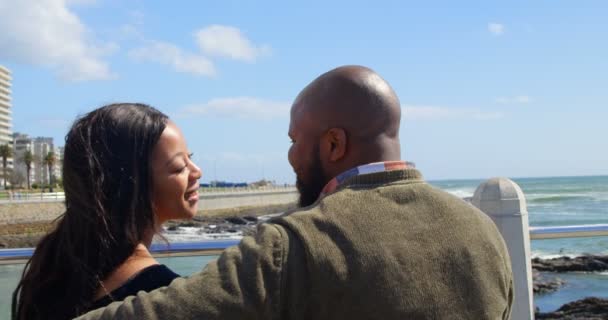 在阳光明媚的日子里 情侣们在栏杆附近的长凳上接吻 美丽的天空和平静的大海在背景4K — 图库视频影像