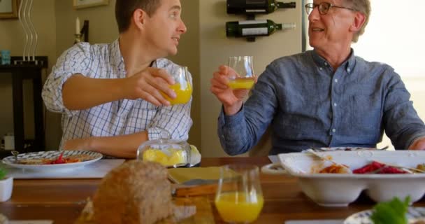 幸福的父子在家里敬酒一杯果汁 坐在餐桌上 有4K — 图库视频影像