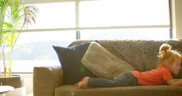 デジタル タブレットを使用して 自宅のリビング ルームでかわいい男の子 のソファーに横たわる裸の少年 — ストック動画