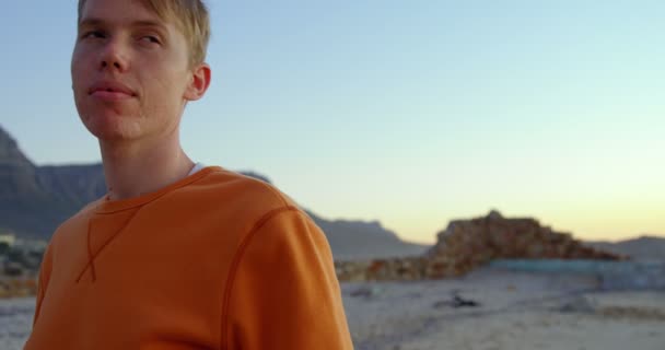 Молодой Заботливый Человек Сидит Пляже Закатное Небо Заднем Плане — стоковое видео