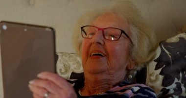 Üst düzey kadın yatakta yatak odasında dijital tablet kullanarak Close-up. Üst düzey kadın yatakta 4 k rahatlatıcı