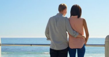 Dikiz çift sakin denize bakarken konuşuyor. 4 k korkuluk yakınındaki bel çevresinde silah ile ayakta