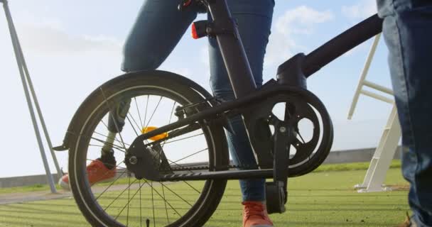 在公园里坐在自行车上的残疾妇女的低谷 背景中美丽的天空4K — 图库视频影像
