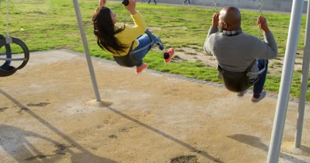 Вид Сзади Пару Играющую Качелях Детской Площадке Парке Пара Веселится — стоковое видео