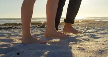 Güneşli bir günde kumsalda yürüyen çift düşük bölümü. Yalınayak 4 k yürüme çift