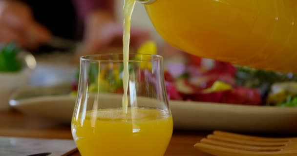 自宅のグラスに注がれているジュースのクローズ アップ のトーストにバターを適用する母 — ストック動画