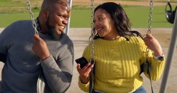 幸せなカップルは 晴れた日に公園で携帯電話を使用して カップルは お互いの対話 — ストック動画