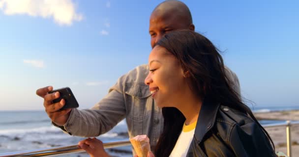 アイスクリームをしながら携帯電話で幸せなカップルを Selfie カップルが楽しんで — ストック動画