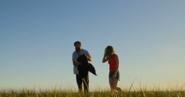 年轻夫妇一起在海滩上散步 背景4K 美丽的天空 — 图库视频影像