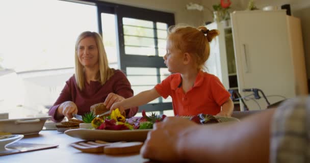 母亲和儿子在餐桌上切了一条面包 微笑的母亲看着儿子 同时帮助她4K — 图库视频影像