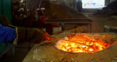 Worker melting molten in furnace at foundry workshop. Worker working in foundry workshop 4k