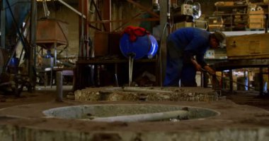 Döküm atölyesinde süpürge ile temizlik işçisi. Metal kalıp 4 k taşıyan iş arkadaşı