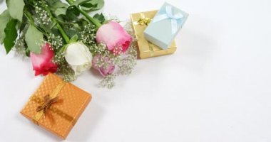 Altın hediye kutuları ve gül buketi. Sürpriz hediye ve çiçek beyaz arka planda 4k