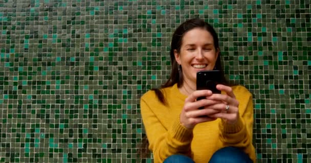 Wanita Berambut Coklat Tersenyum Mengirim Pesan Teks Dinding Mosaik Hijau — Stok Video