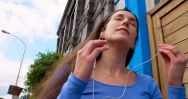 Mutlu güzel genç kadın cep telefonu müzik dinleme. Sokak 4 k üzerinde yürüyen kadın