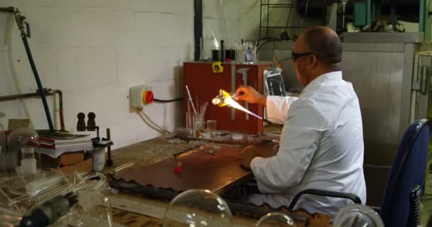 ガラス工場でガラスを吹いている中高年の男性労働者の側面図です 成熟した男性労働者加熱ガラス — ストック動画