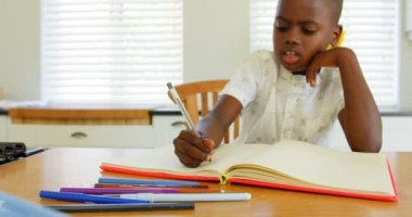 Önden görünüm siyah erkek çocuk ödevini evde yapıyor. 4 k masada oturan düşünceli siyah erkek