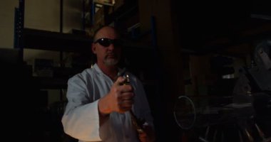 Erkek işçi aydınlatma cam üfleme meşale cam fabrikasında önden görünümü. Cam üfleme meşale 4 k tutan olgun erkek işçi