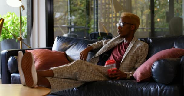 年轻的黑人商人在现代办公室看手机 年轻的黑人商人在沙发上放松4K — 图库视频影像