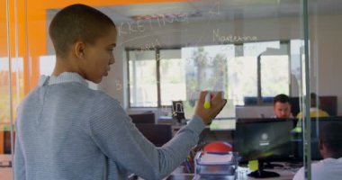 Arka görüş genç beyaz kadın çift yazma cam duvar modern ofis. Dijital tablet 4 k tutan genç beyaz kadın yönetici