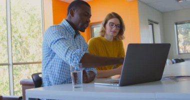Genç modern ofis içinde laptop üzerinde tartışırken yarış iş arkadaşları karışık. Genç yarış iş arkadaşları birlikte çalışan 4 k karışık