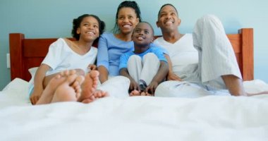 Siyah aile evde yatak odasında televizyon izlerken önden görünümü. Siyah aile rahatlatıcı yatak 4k