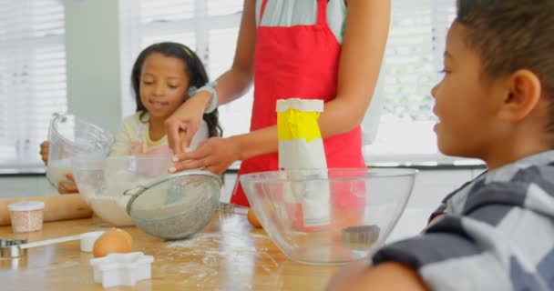 自宅のキッチンで料理を準備する彼の子供と母親が黒 黒い医者食糧 の準備で彼女のお母さんを手伝って — ストック動画