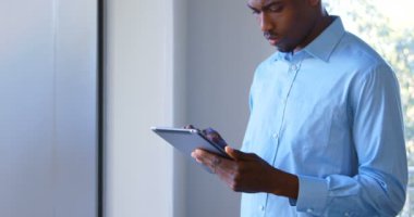 Modern Office dijital tablet üzerinde çalışan genç siyah erkek yönetici. Düşünceli genç siyah erkek yönetici Dış Saha 4 k arıyorsunuz