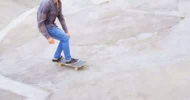 Kaykay Parkı içinde rampa üzerinde kaykay hile yaparak Genç beyaz adam yan görünüm. Adam 4 k gün ışığında kaykay