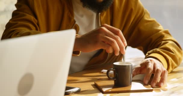 カフェでスプーンで一杯のコーヒーをかき混ぜアジア青年のフロント ビュー のカフェで座っている若いアジア男 — ストック動画