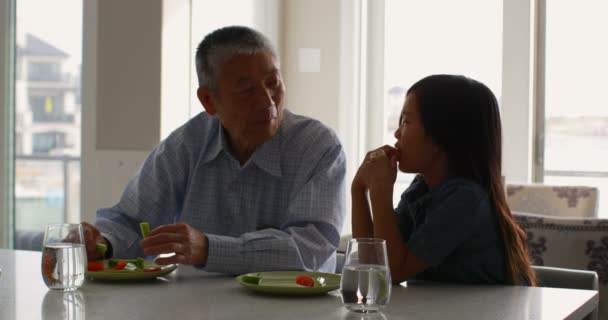 前面可以看到可爱的亚洲孙女和老爷爷在餐桌上吃东西 餐桌4K 上的餐盘和一杯水 — 图库视频影像