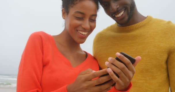 Vista Frontal Jovem Casal Negro Sorrindo Revisando Fotos Celular Praia — Vídeo de Stock