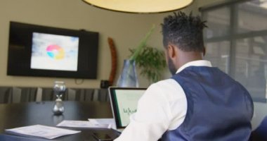 Dikiz elle office içinde laptop üzerinde çalışırken başının arkasında genç siyah işadamı. İşadamı konferans salonundaki 4k masada rahatlatıcı